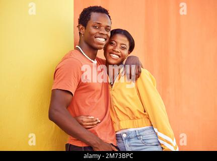 Coppia nera, gioventù e moda con gen z, abbraccio e insieme a colore e ritratto su sfondo parete. Uomo nero, donna nera e giovane con Foto Stock