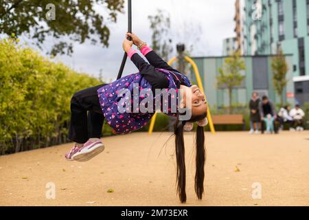 Ragazza sorridente che oscilla su una corda in un parco giochi Foto Stock