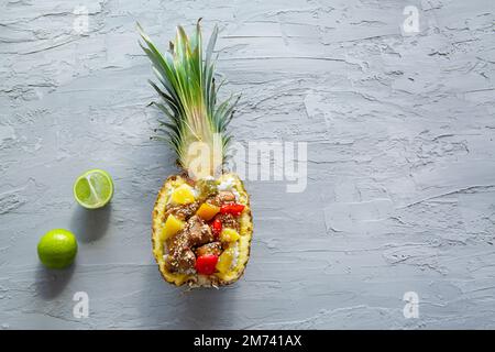 Riso all'ananas in stile asiatico o messicano con pollo e verdure in salsa agrodolce, vista dall'alto. Spazio per la copia, spazio libero per il testo. Foto Stock