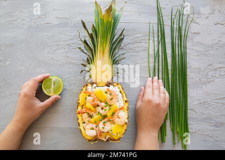 Riso asiatico in ananas con gamberi su sfondo grigio, vista dall'alto. Gustoso piatto orientale. Foto Stock
