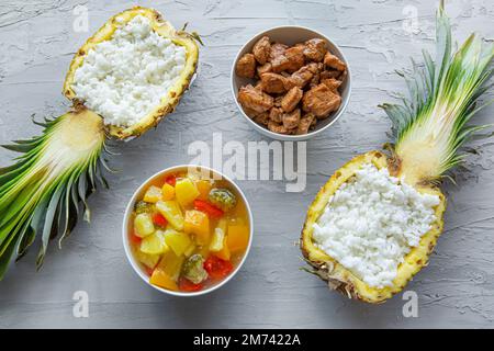Riso in ananas con pollo e verdure in salsa agrodolce su fondo di cemento, vista dall'alto. Foto Stock
