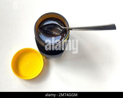 Primo piano di un vaso di marmite appena aperto con un cucchiaio, fondo bianco Foto Stock