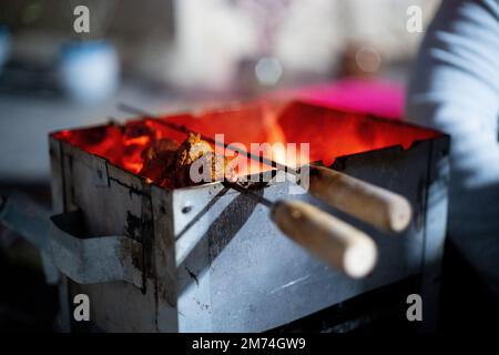 Verdure e anananas che sono arruolato arrostito su legno e carbone fuoco in scatola di metallo nel freddo delhi inverni come Street food Foto Stock