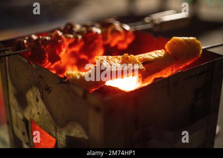 Verdure e anananas che sono arruolato arrostito su legno e carbone fuoco in scatola di metallo nel freddo delhi inverni come Street food Foto Stock