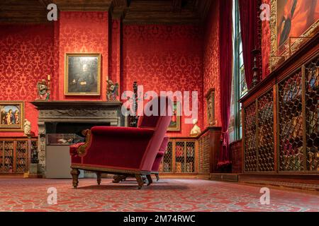 Foto dell'interno di una delle camere della Morgan Library di New York City con una sedia di velluto rosso e una bella carta da parati sulle pareti. Foto Stock