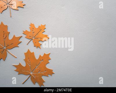 Foglia di acero arancione in metallo tagliata su fondo in cemento con spazio per la copia per la pubblicità. Autunno, giorno di ringraziamento e concetto di inverno. Foto Stock
