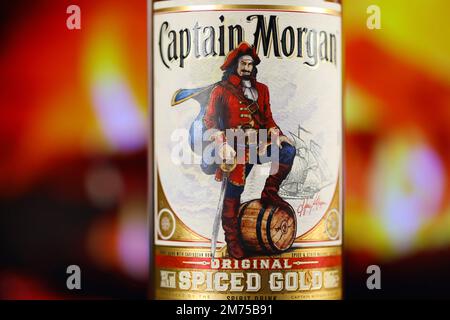 KIEV, UCRAINA - 4 MAGGIO 2022 Capitano Morgan bottiglia di alcol originale su tavolo di legno con camino rosso sullo sfondo. Produzione di alcool Elite Foto Stock