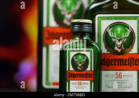 KIEV, UCRAINA - 4 MAGGIO 2022 Jagermeister bottiglia di alcol originale su tavolo di legno con camino rosso sullo sfondo. Produzione di alcool Elite Foto Stock