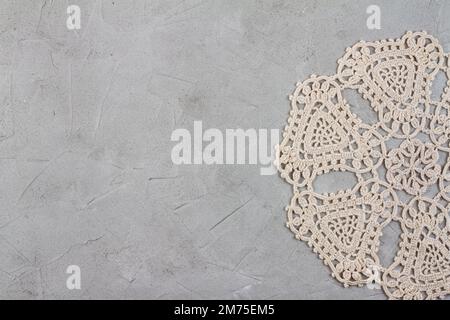 Bel ricamo di tovagliolo vecchio di filo beige fatto a mano su fondo di cemento grezzo in stile vintage Foto Stock