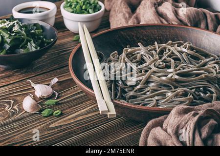 Ancora vita dei tradizionali noodle di soba giapponesi con nori (alghe commestibili) e salsa di soia, su una superficie di legno con fuoco selettivo Foto Stock