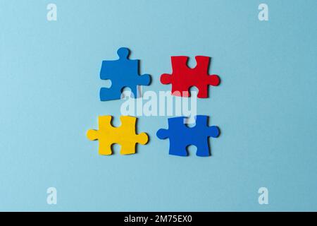 Pezzi di puzzle blu, giallo, rosso su sfondo azzurro. Concetto di giornata di consapevolezza dell'autismo mondiale. Vista dall'alto, spazio di copia Foto Stock
