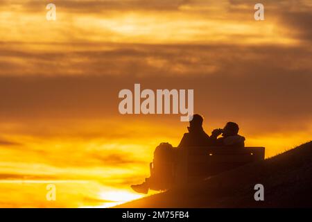 Wien, Vienna: Tramonto del fuoco, 2 uomini seduti su panchina bere birra da lattine, persone come silhouette nel 19. Döbling, Vienna, Austria Foto Stock