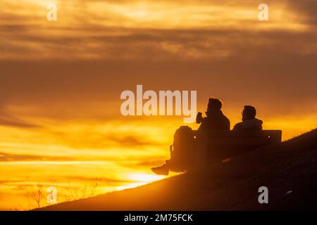 Wien, Vienna: Tramonto del fuoco, 2 uomini seduti su panchina bere birra da lattine, persone come silhouette nel 19. Döbling, Vienna, Austria Foto Stock