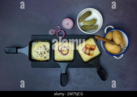 Raclette, formaggio a raclette fuso in padelle e ingredienti Foto Stock