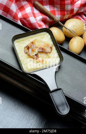 Raclette, formaggio a raclette fuso con pancetta in padelle e ingredienti Foto Stock