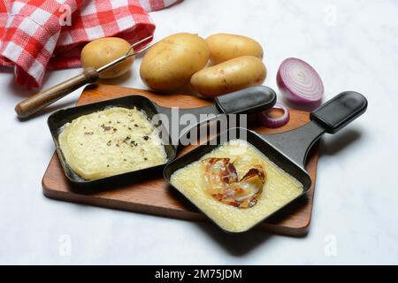 Raclette, formaggio a raclette fuso in padelle e ingredienti Foto Stock