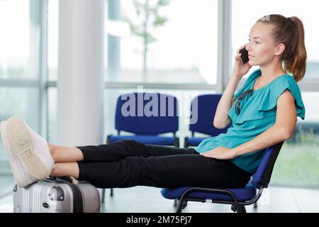 giovane donna con telefono in attesa di aereo Foto Stock