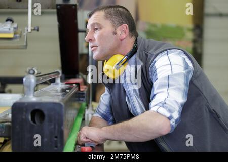 man monta componenti elettronici su una macchina in fabbrica Foto Stock