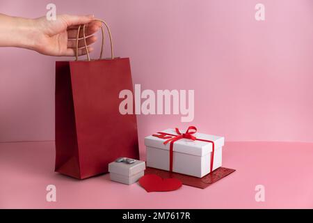 St Borsa di carta rossa per San Valentino, regali in scatole con nastro. Spazio di copia. Mock up per la Festa della mamma. Dare presente o sorpresa Foto Stock