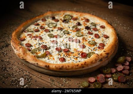 deliziosa pizza jalapenos con salsicce. tavolo di legno scuro Foto Stock