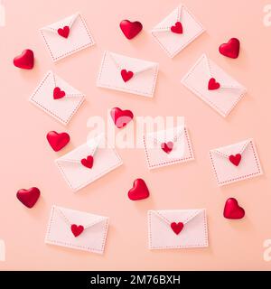 Buste in feltro bianco con cuori rossi su sfondo rosa chiaro, vista dall'alto Foto Stock