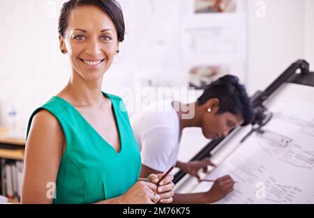 L'architettura è la sua passione. Ritratto ritagliato di un architetto femminile con la sua collega che lavora in una tavola da disegno. Foto Stock