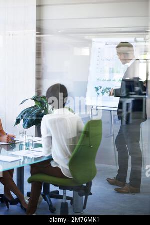 Theyre nel think tank. un uomo d'affari che presenta i dati in una sala riunioni con pareti in vetro. Foto Stock