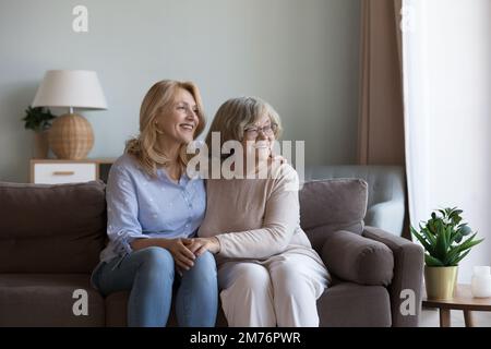 Donna figlia felice e mamma anziana seduti sul divano Foto Stock