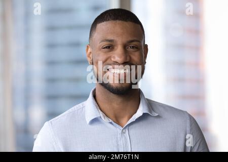 Uomo africano che posa sorriso interno fissando la camma Foto Stock