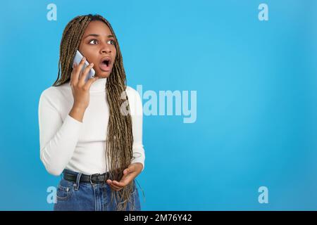 Donna africana con un'espressione sorpresa che parla con il cellulare Foto Stock