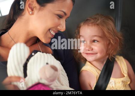 La famiglia non è una cosa importante, è tutto. Una bella madre e figlia si tengono intrattenuti mentre si viaggia sul retro di un'auto. Foto Stock