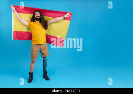 Uomo con gamba protesica che alza una bandiera spagnola Foto Stock