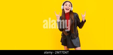tutta la lunghezza del bambino freddo in cuffie su sfondo giallo. Ritratto per bambini con cuffie, poster orizzontale. Ragazza che ascolta musica, banner con Foto Stock