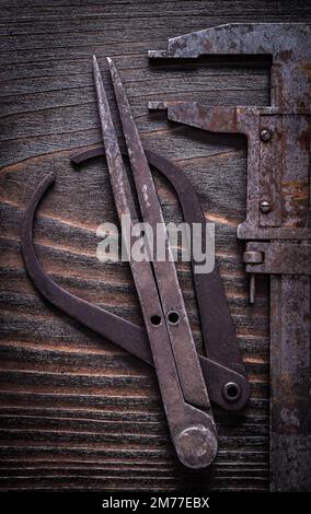 Pinze di misurazione in stile retrò arrugginito su fondo vintage in legno scuro concetto di costruzione. Foto Stock