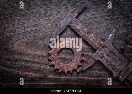Pinze di misurazione in stile retrò arrugginito con pignone su fondo in legno scuro vintage. Foto Stock