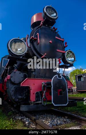Locomotiva a vapore vista dalla parte anteriore. Uno scatto dal basso verso l'alto che mostra l'oggetto contro un cielo blu Foto Stock