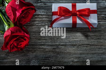 Scatole regalo bianche rose rosse su asse di legno. Foto Stock