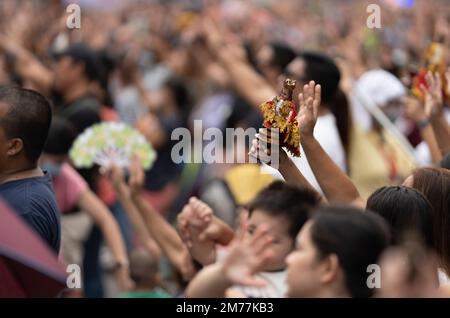 I cattolici filippini agitarono le mani in aria e sorreggono le statuine di Santo Nino mentre la canzone religiosa Batobalani sa Gugma viene suonata al B Foto Stock