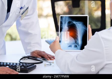 Concetto di radiologia e medicina. il medico spiega i risultati della scansione polmonare sullo schermo del tablet digitale al paziente con un lungo covid Foto Stock