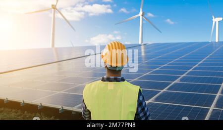 Ingegnere che lavora per un'azienda agricola ad energia alternativa - concetto di turbine eoliche e pannelli solari - Focus sul casco Foto Stock