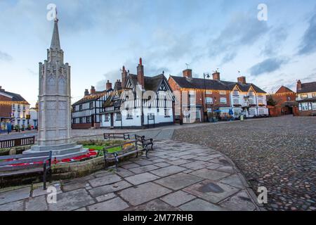 La piazza del mercato acciottolata nella città di Sandbach in Cheshire con il suo memoriale di guerra cenotafio e la locanda in bianco e nero Foto Stock