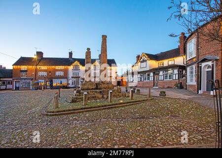 L'antica piazza del mercato acciottolata, illuminata a giorno, nella città del mercato di Cheshire a Sandbach, con le croci sassone e due vecchie locande per le carrozze di notte Foto Stock