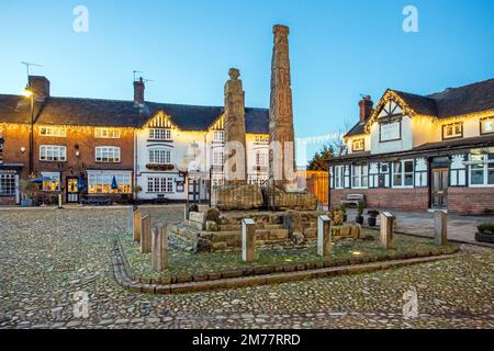 L'antica piazza del mercato acciottolata, illuminata a giorno, nella città del mercato di Cheshire a Sandbach, con le croci sassone e due vecchie locande per le carrozze di notte Foto Stock