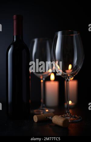 Elegante vino rosso in vetro e una bottiglia di vino in sfondo nero Foto Stock