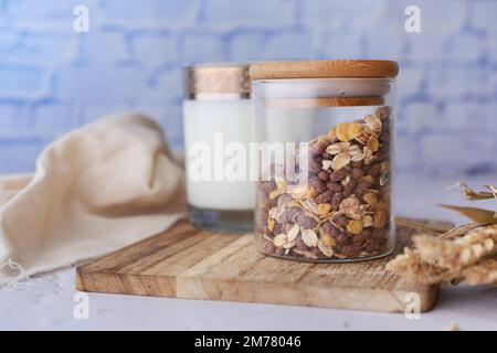 Musli fatti in casa in un vasetto e un bicchiere di latte sul tavolo Foto Stock