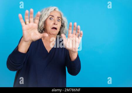 Donna matura che gestura con le mani nella paura Foto Stock
