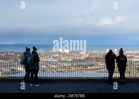 Edimburgo, Scozia, Regno Unito. 8th gennaio 2023. I visitatori della collina di Calton si sono avvolti contro il freddo vento e le mutevoli condizioni atmosferiche. Vista verso nord sui tetti della città verso il quarto estuario. Credit: Craig Brown/Alamy Live News Foto Stock