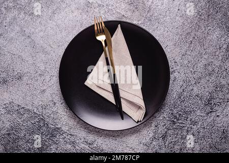 Pulire la piastra nera vuota con le posate. Spazio di copia, mock-up, vista dall'alto. Concetto per menu con utensil. Foto Stock