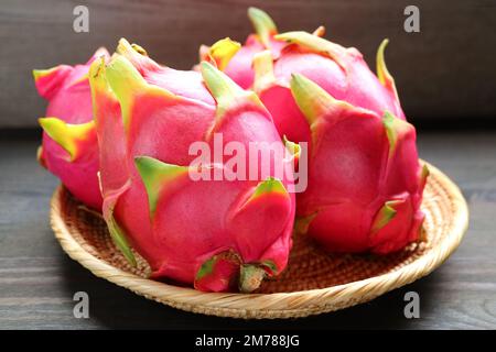 Un mucchio di fresche e vivaci frutti rosa del drago in un cestino Foto Stock