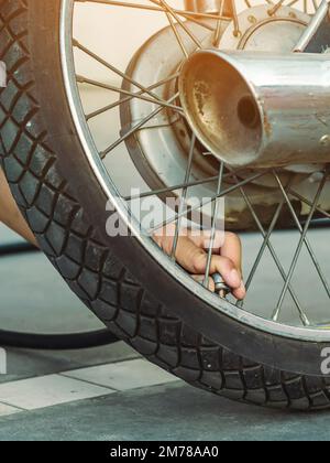 Mani di un uomo controllare la pressione del generatore di gas e gonfiare uno pneumatico su una motocicletta con un compressore pneumatico. Man controllo della pressione dell'aria e riempimento della pressione dei pneumatici Foto Stock
